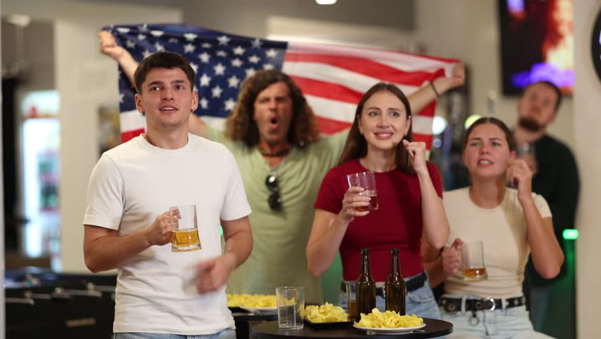 Group of fans of the United States national team spend time in a bar, shouting chants, supporting their favorite team. High quality 4k footage