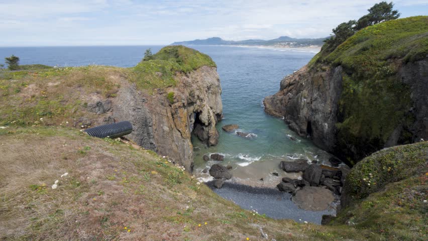 Ocean Bay Inlet, Secluded Mini Beach Below Cliffs. Yaquina Head, West Coast, Newport Oregon, USA. Looking North Towards Otter Rock. Corrugated Plastic Drainage Pipe Sits Above the Water.