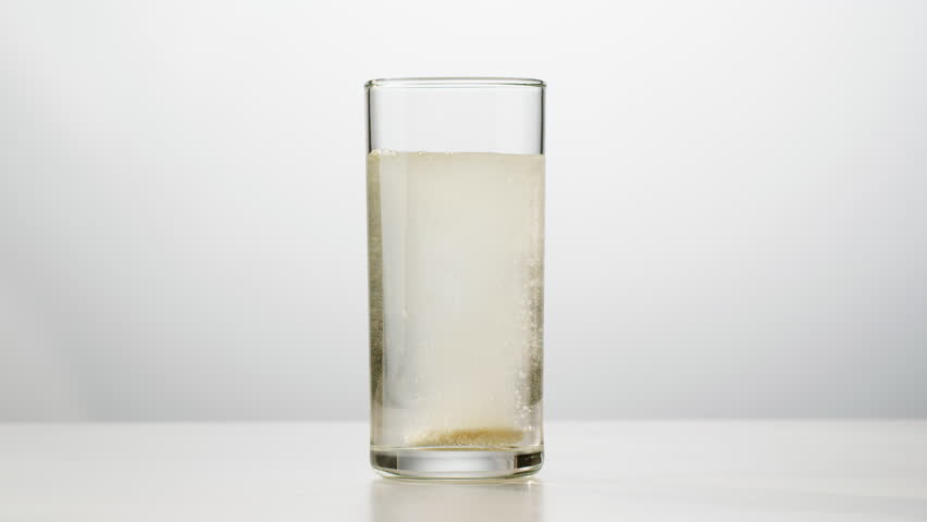 Effervescent tablet vitamin C aspirin nutritional supplements in glass with yellow carbonated water, sport medication, healthy morning. Healthy vitamins D drugs