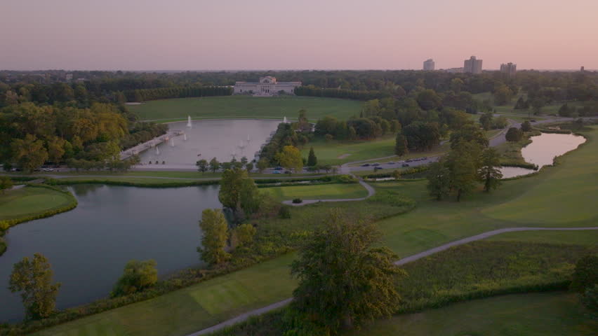 Aerial of the St. Louis Art Museum in Forest Park with a pan over golf course facing downtown Clayton skyline in St. Louis, Missouri at sunset.