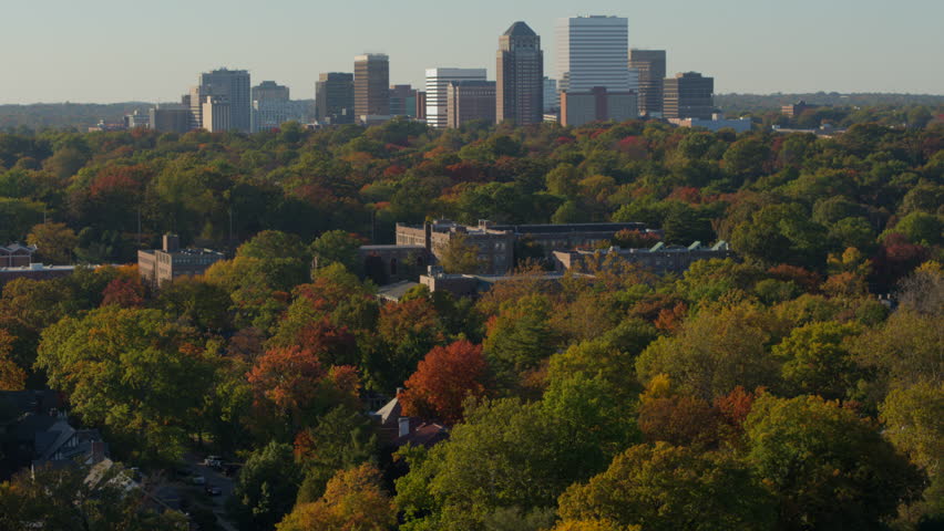 Aerial of neighborhood and downtown Clayton skyline in St. Louis, Missouri with slow rise and drift on a beautiful day in Autumn with a clear blue sky.