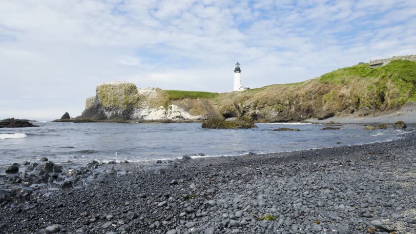 Waves Crashing on Back Rock Beach at Tranquil White Light-House on a Cliff in a Bay. Beautiful Calm Landscape. West Coast Pacific Ocean, Oregon Coast. Pan Left Calming Relaxing View. Yaquina Head, OR