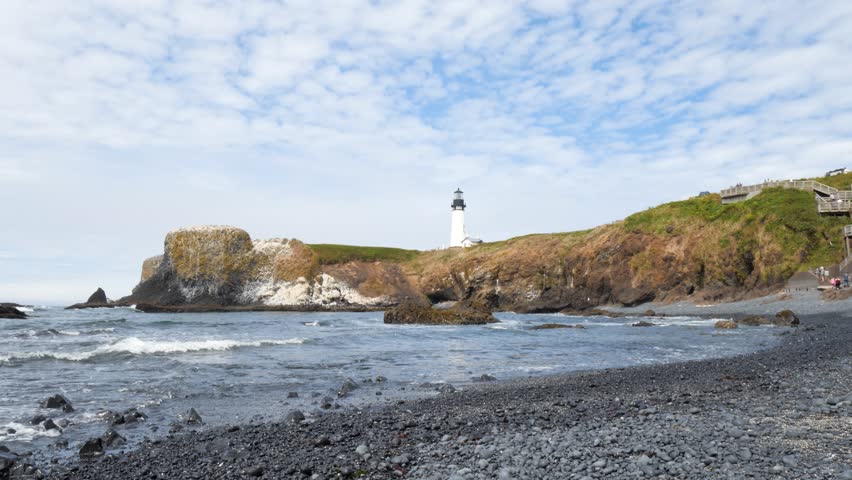 Waves Crashing on Back Rock Beach at Tranquil White Light-House on a Cliff in a Bay. Beautiful Soothing Landscape. West Coast Pacific Ocean, Oregon Coast. Calm Steady Tripod Shot. Yaquina Head, OR