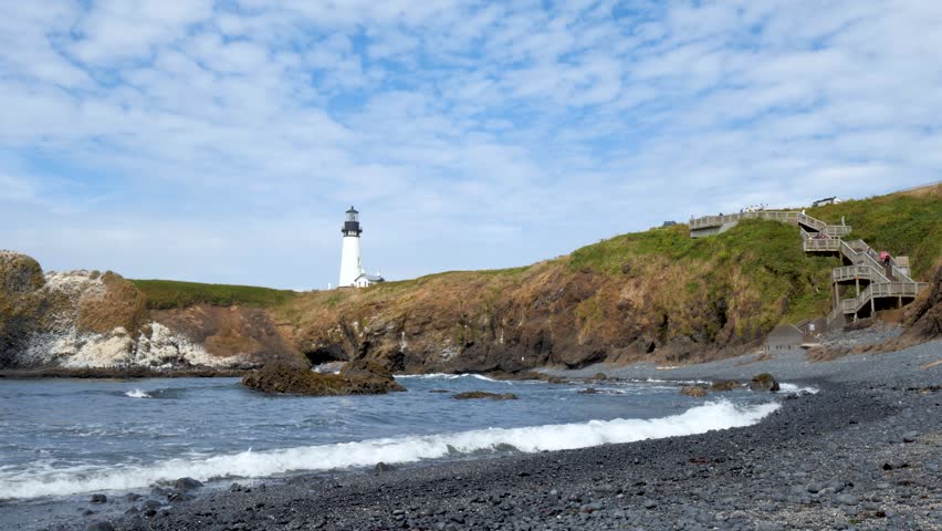 Waves Crashing in Slow Motion at Tranquil White Light-House on a Cliff in a Bay. Beautiful Calming Landscape. West Coast Pacific Ocean on Oregon Coast. Pan Left Calming Relaxing View. Yaquina Head, OR