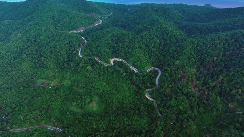 Aerial view of Zigzag road on Puerto Princesa South Road near Turtle Bay during cloudy day. Philippines, Palawan. Dense green forest landscape.