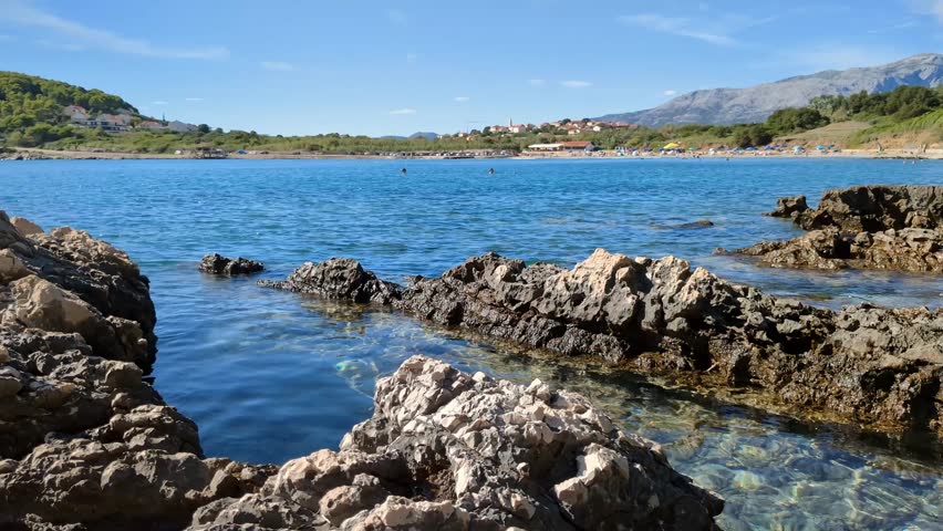 Peaceful sea shore on rocky beach, mountains background, calm nature scenery, Mediterranean