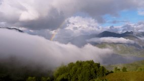 A breathtaking view of a misty mountain landscape, with clouds rolling over lush green valleys and a shimmering lake below. A vibrant rainbow arches across the sky, adding a magical touch. - Powered by Shutterstock - Get 15% off with code: PIKWIZARD15
