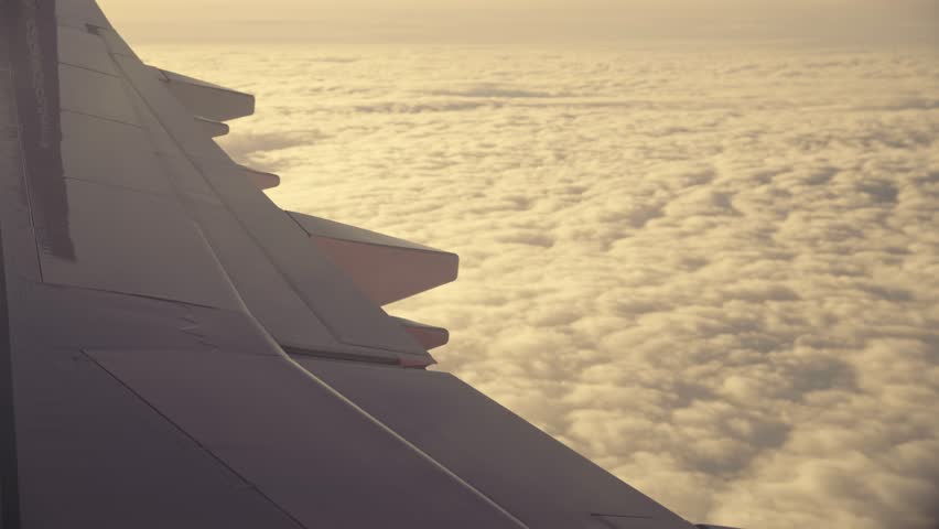Airplane flight. Traveling by airplane. Wing of an airplane flying above the clouds with sunset sky. View from the window of the plane.