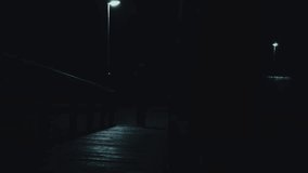 dark silhouette of a man walks under a lantern.crime mood. man walks on a wooden bridge in the dark.Dark mysterious atmosphere. Noir mood.  - Powered by Shutterstock - Get 15% off with code: PIKWIZARD15