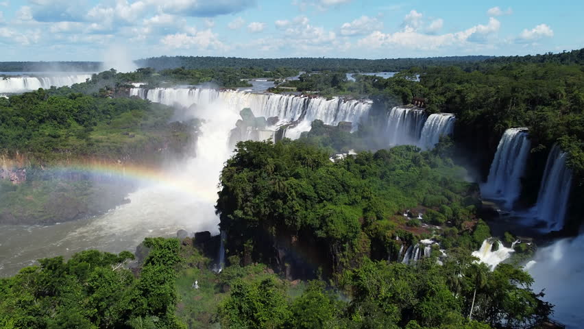 Aerial rising shot of large Iguazu Falls in Argentina and Brazil. Sunny day in South America. Amazon rainforest with tropical plants. Wide shot.
