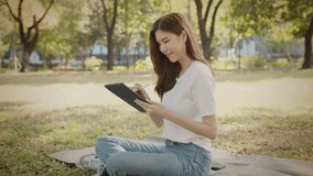 Attractive Freelance Woman Relaxing and Working Remotely in Nature, Happy Female Professional on a Video Call, Tech-Savvy Female Learning Online. Young Woman Reading and Communicating a Tablet - Powered by Shutterstock - Get 15% off with code: PIKWIZARD15