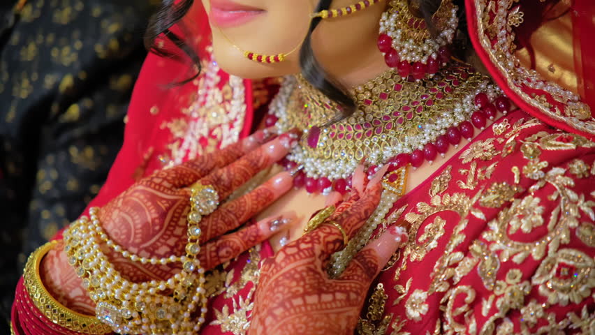 Traditional henna painting on woman hands with bangles, bracelets in Red color traditional clothes. Close up Move camera