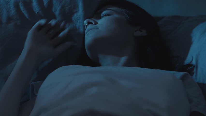 Nightmare anxiety. Bad dream. Sleep disorder. Disturbed scared woman waking up from night terror in bed late in dark bedroom.