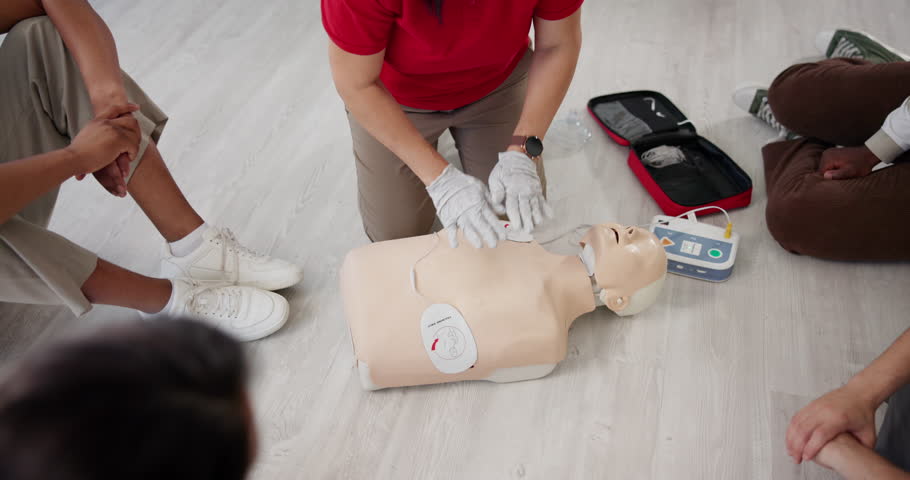 Paramedic, hands and talking with dummy for CPR class, first aid training or emergency healthcare practice on floor. Person, trainer or teaching with group for life saving lesson or rescue practical