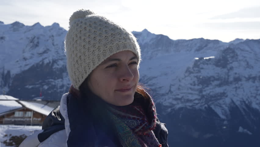 Meditative woman in 30s closing eyes in contemplation amidst mountains in high peak. Contemplative person wearing winter clothes reflecting on life, peaceful solitude