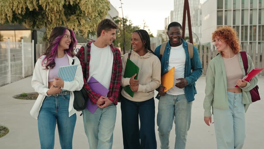 Cheerful young multiethnic college students talking and walking after classes on University campus 