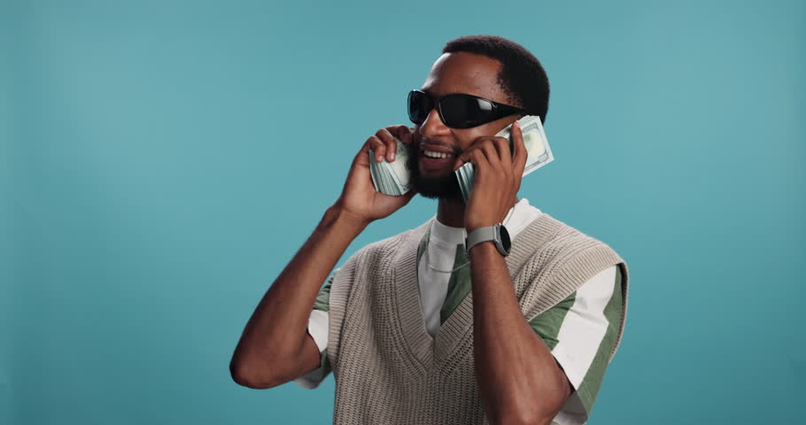 Happy, black man and money with cash for financial freedom, rapping or investment on a blue studio background. Male person, rapper or cool model with smile, bills or dollars for rich, wealthy or fame