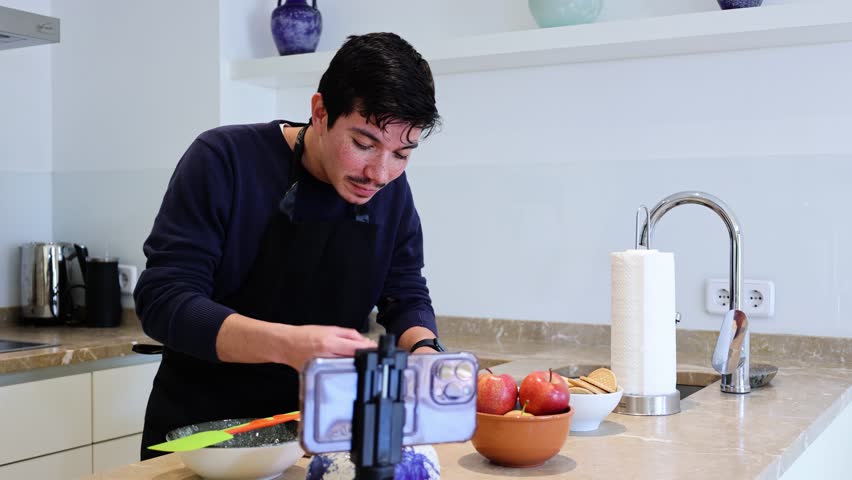 Video of Cheerful young man eating apples making a tutorial of a recipe for a dessert with apples and cookies at home - Powered by Shutterstock - Get 15% off with code: PIKWIZARD15