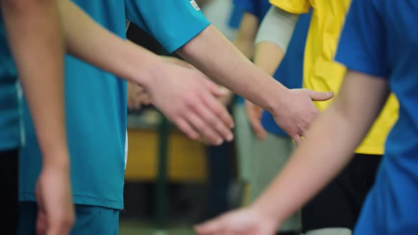 Volleyball players shake hands under the net before the start of a match. A moment of sports etiquette, friendliness and team spirit.