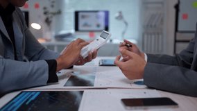 Businessmen discussing numbers and finances while using a calculator in a corporate office setting - Powered by Shutterstock - Get 15% off with code: PIKWIZARD15