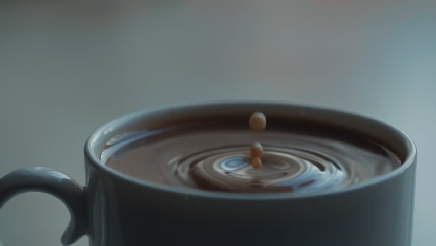 A steaming coffee cup captured beautifully in soft, warm light for an inviting ambiance. Super slow motion