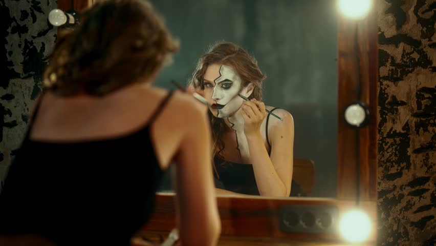 Natural beauty and fake personality, woman doing makeup in dressing room. Crisis of identity and playing role for society, portrait of young adult woman drawing another face on herself, stay yourself