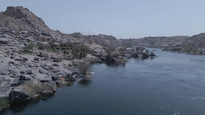 Daytime drone footage of the Nile River in Aswan, Egypt, featuring small islands and scenic views. Captures natural beauty and iconic river landscape.