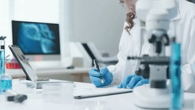 Female scientist writing notes for experimental results test biological from microscope and checking chemical at a test tube for research on pharmacy medical for and antibody for disease and virus - Powered by Shutterstock - Get 15% off with code: PIKWIZARD15