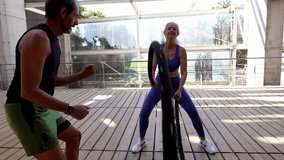 Happy senior woman exercising with battle ropes with her personal trainer in a modern gym with wooden floor and glass walls, hugging him at the end of the training session - Powered by Shutterstock - Get 15% off with code: PIKWIZARD15