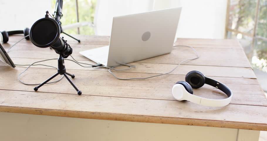 Podcast setup with laptop, microphone, and headphones on wooden desk at home. Podcasting, recording, home studio, equipment, sound, audio
