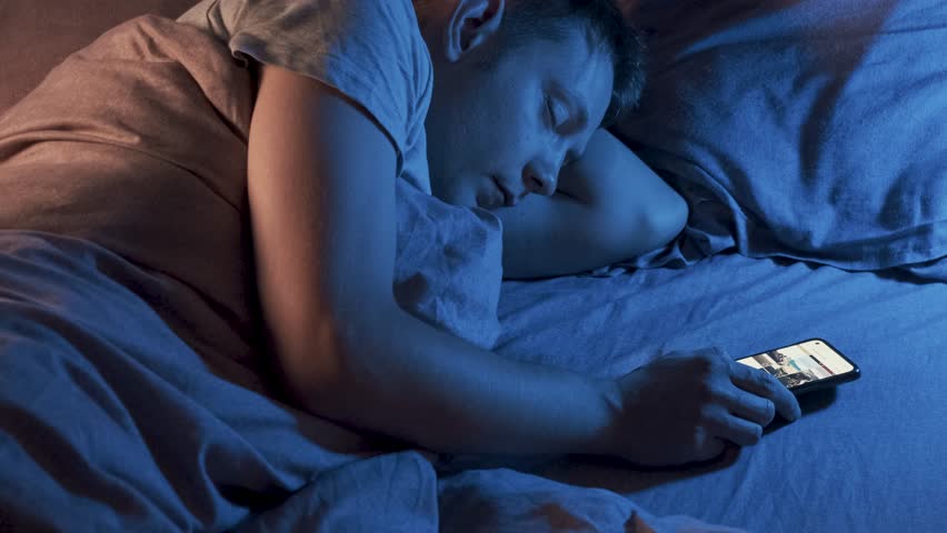 Caucasian man fall asleep in bed at home using mobile phone. Tired, exhausted male sleeping with smartphone in bedroom. Smartphone, internet, social media, gadget addiction concept