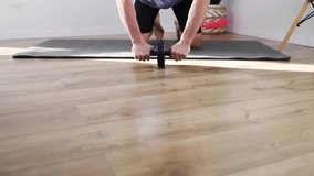 Handsome middle aged man doing exercise with abs wheel on mat. Athletic man in sportswear doing fitness workout in living room at home. Bodybuilding, fitness workout, healthy lifestyle concept. - Powered by Shutterstock - Get 15% off with code: PIKWIZARD15