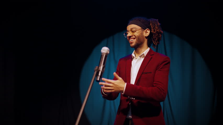 Award winner taking his award on stage, portrait of happy mixed race man. Thankful speech of joyful young adult man, happy smile on male face, successful musician, businessman or comedian, medium shot