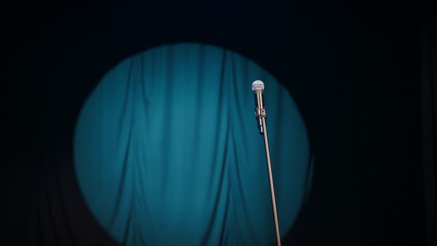Nobody on stage, only mic on stand and round of bright light in darkness. Nightclub with strange for performance, waiting for start of musical concert or stand-up comedy performance, talent show