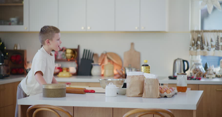 A young boy excitedly runs into the kitchen, preparing to bake gingerbread cookies for Christmas with joy and enthusiasm.