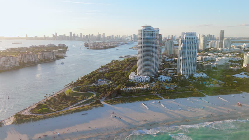 Stunning aerial view highlights a beautiful Miami Beach neighborhood with luxurious homes, sparkling pools, and palm trees, all set under the bright sunshine of a perfect sunset condition. Florida USA