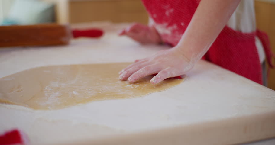 A young boy carefully cuts out patterns in dough and prepares to bake delicious gingerbread cookies.