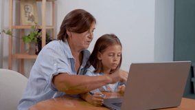 Young girl and her grandmother engage with laptop at home discovering new things together. This moment symbolizes importance of technology in bridging generational gaps and enhancing family bonds - Powered by Shutterstock - Get 15% off with code: PIKWIZARD15