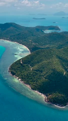 Breathtaking aerial view of a tropical paradise showcasing lush greenery and pristine waters. Vertical video