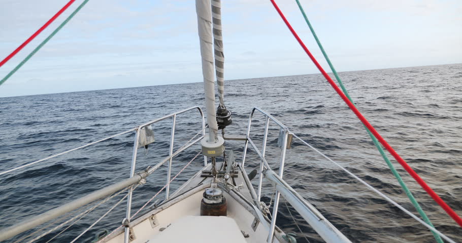 Bow of sailboat with two furling sails motoring across the Bay of Biscay