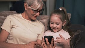 Grandmother and granddaughter sharing joyful moments while exploring a smartphone together connecting generations through technology - Powered by Shutterstock - Get 15% off with code: PIKWIZARD15