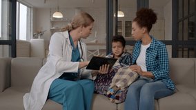 Positive female physician in uniform explaining treatment using digital tablet ,showing medical procedures to afraid sick school age African American boy and worried mother during visit. - Powered by Shutterstock - Get 15% off with code: PIKWIZARD15