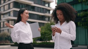 Two women African American Asian Korean businesswomen business females coworkers colleagues ignoring addicted mobile phone smartphone talk tell indifferent disinterested city stuck outdoor urban girls - Powered by Shutterstock - Get 15% off with code: PIKWIZARD15