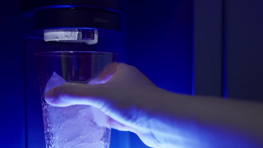 Close up a woman hand pressing the button on an automatic ice dispenser in a refrigerator, Freezer automatic ice maker