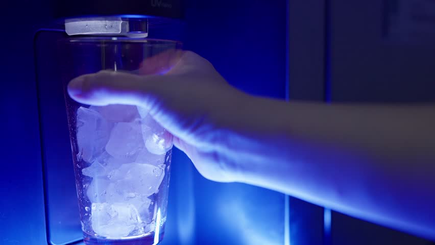 Close up a woman hand pressing the button on an automatic ice dispenser in a refrigerator, Freezer automatic ice maker