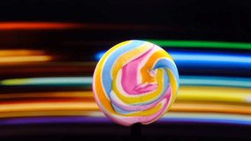 A vibrant, multicolored swirl lollipop stands in sharp focus against a blurred background of horizontal rainbow stripes, creating a visually striking contrast - Powered by Shutterstock - Get 15% off with code: PIKWIZARD15
