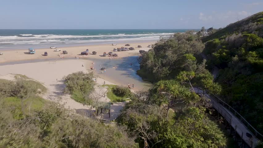 Aerial view of jeep driving on the sandy beach with people enjoying the seaside, Fraser Island, Australia.