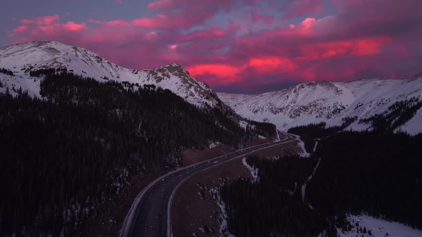 Rocky Mountains Winter solstice Colorado vibrant purple pink cloudy skies setting sunset aerial drone i70 highway cars trucks traffic Coon Hill Parshall Eisenhower tunnel Continental Divide upwards