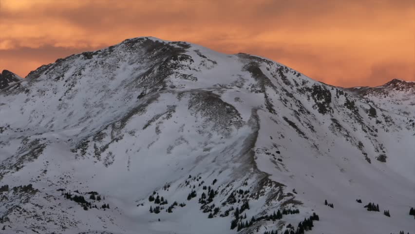 Glorious purple high elevation Rocky Mountains Winter solstice Colorado setting sunset orange vibrant cloudy skies aerial drone i70 Coon Hill Parshall Eisenhower tunnel Continental Divide pan left