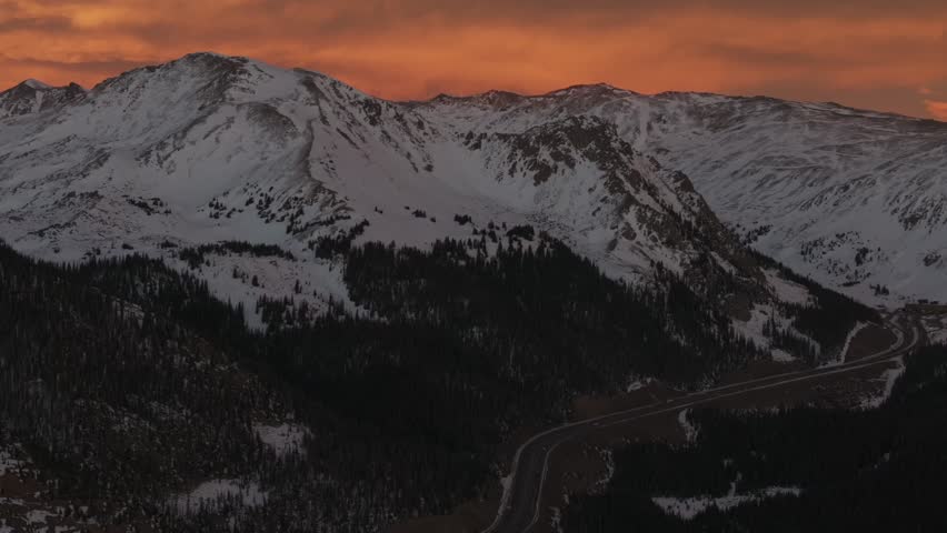 Rocky Mountains Winter solstice Colorado vibrant orange cloudy skies setting sunset aerial drone i70 highway cars trucks traffic Coon Hill Parshall Eisenhower tunnel Continental Divide forward pan up